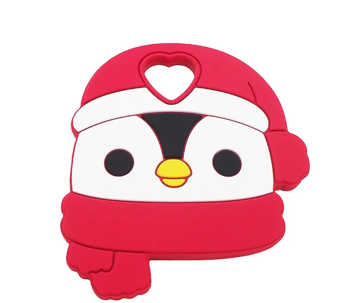 A chewable teether in the design of a penguin head. The penguin has a red scarf and a red toque with a heart shaped hole in the toque for a necklace cord.
