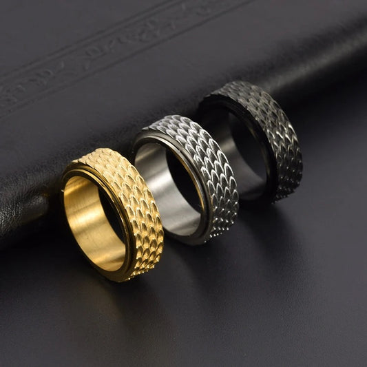 Three spinnable rings on a black background. They are gold, silver and then black. Each has a scale pattern on them.