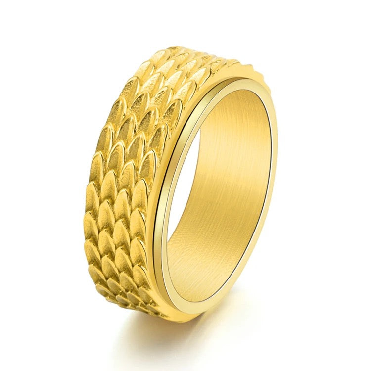 A close up of the gold spinner ring. There is a scale pattern on it that represents dragon scales.