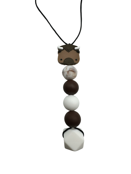 A chewable bead necklace with a bison bead at the top, there are four round beads following it in the following colours: marble brown, brown, white, brown. There is a large hexagon white bead at the bottom.