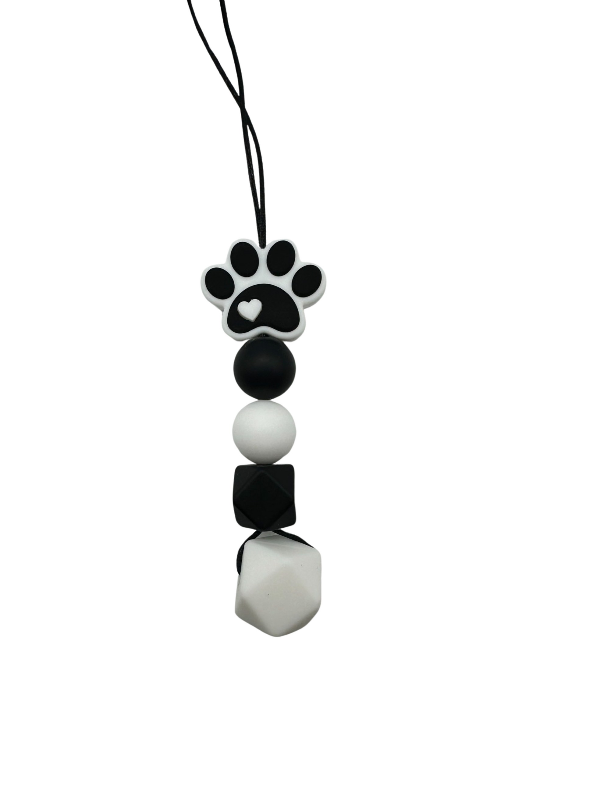 A chewable bead necklace. There is a black and white paw print at the top and then a black round bead followed by a white round bead. There is then a small black hexagon bead and a large white hexagon bead.
