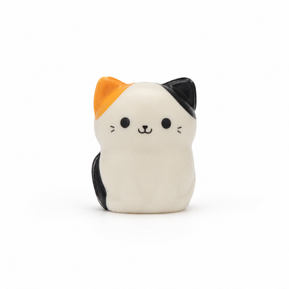 A small squish cat with a tri-color calico pattern, featuring a white-colored body, an orange ear, and a black ear, set against a plain white background.