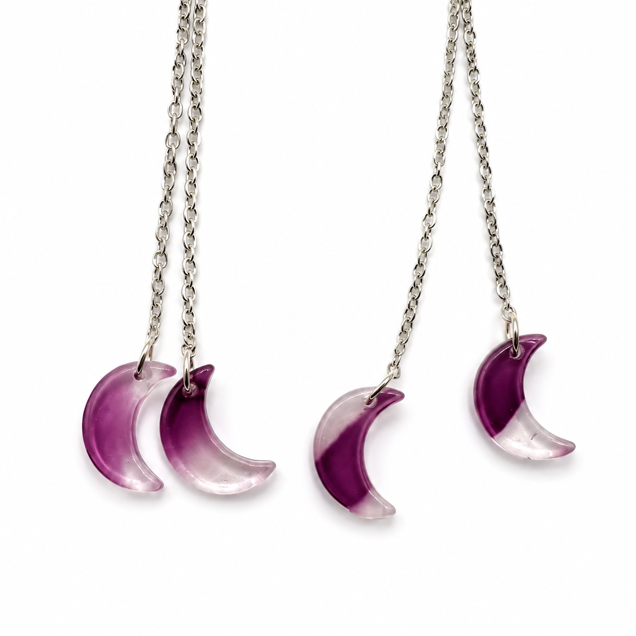 Close-up of a pair of silver-tone chain earrings, each featuring two translucent crescent moon charms that fade from deep purple to clear.