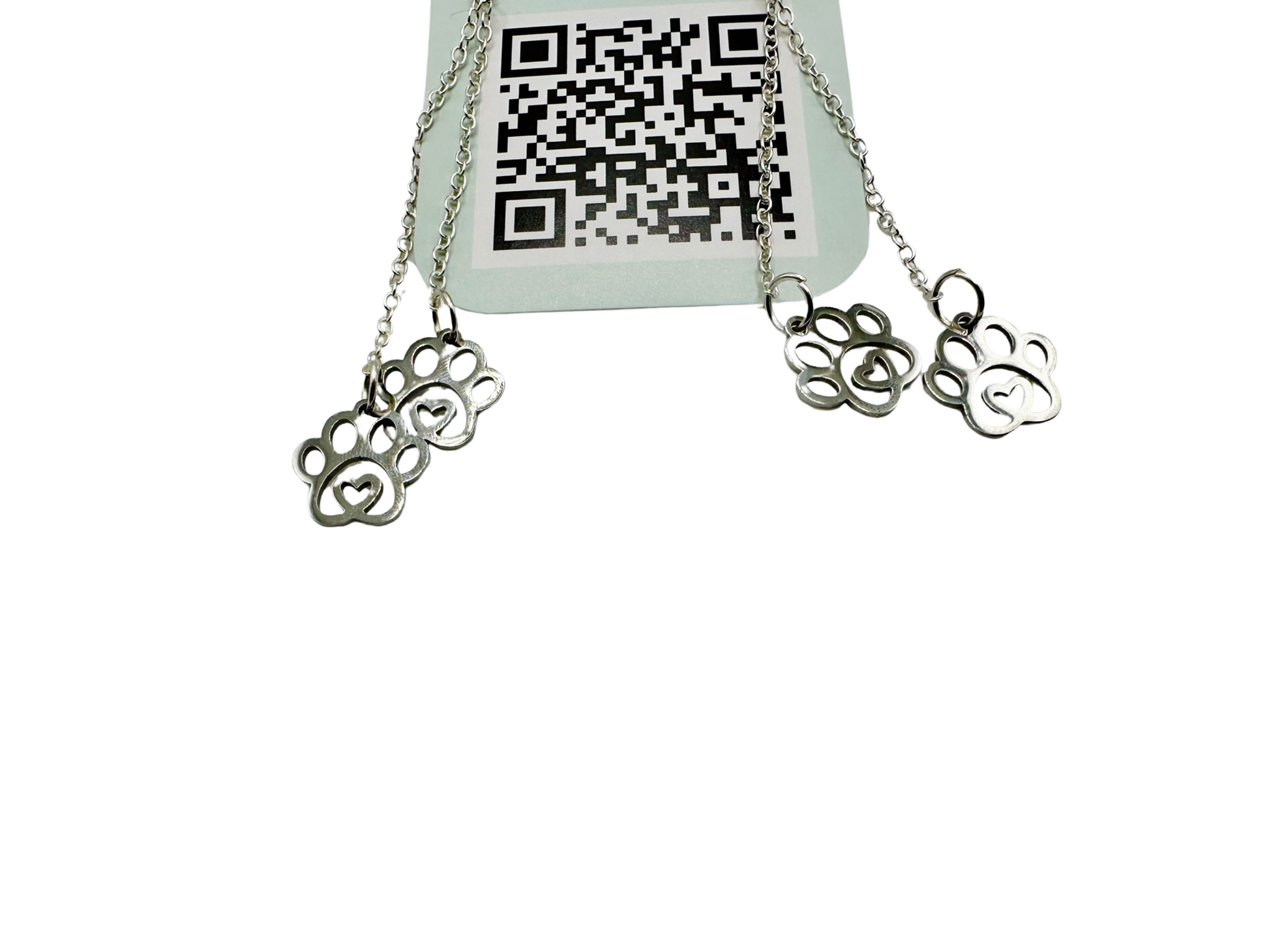 A pair of silver fidget earrings on a blue business card. The earrings have two dangling chains on each side. At the end of the chains are silver pawprint charms with a heart in the middle. The earrings are designed to be pulled back and forth. 