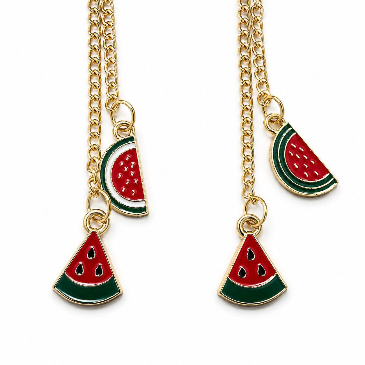 Close-up of a pair of gold-tone chain earrings, each featuring one triangular watermelon charm and one rounded watermelon-slice charm in red, green, white, and gold.
